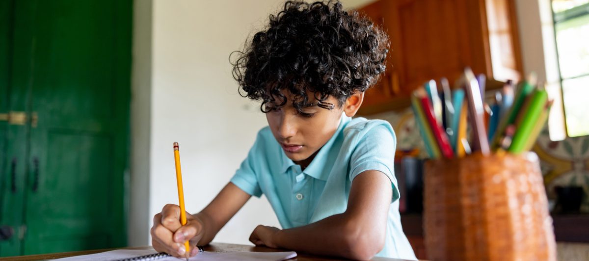 a young child sitting at their desk, completing a money-smart workbook.