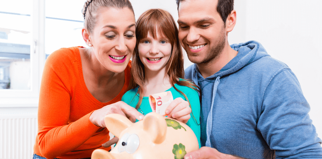 A white mother, daughter, and father in a line putting money into a piggy bank, setting their financial goals for the year